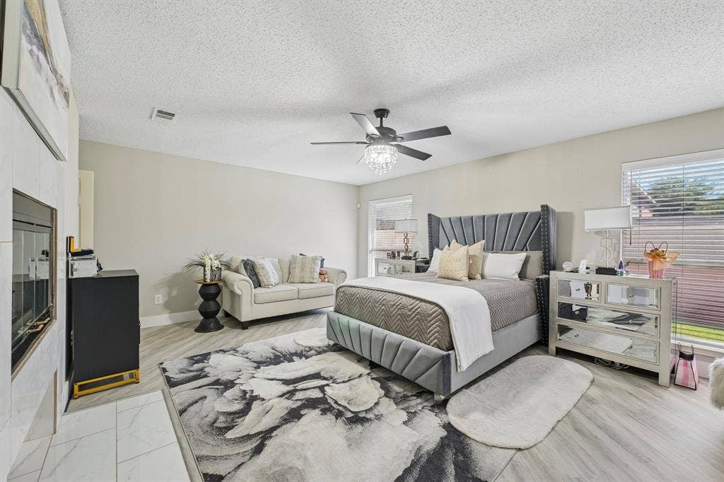 Contemporary fireplace with a tile surround, wood-finish flooring, and a ceiling fan with integrated lighting