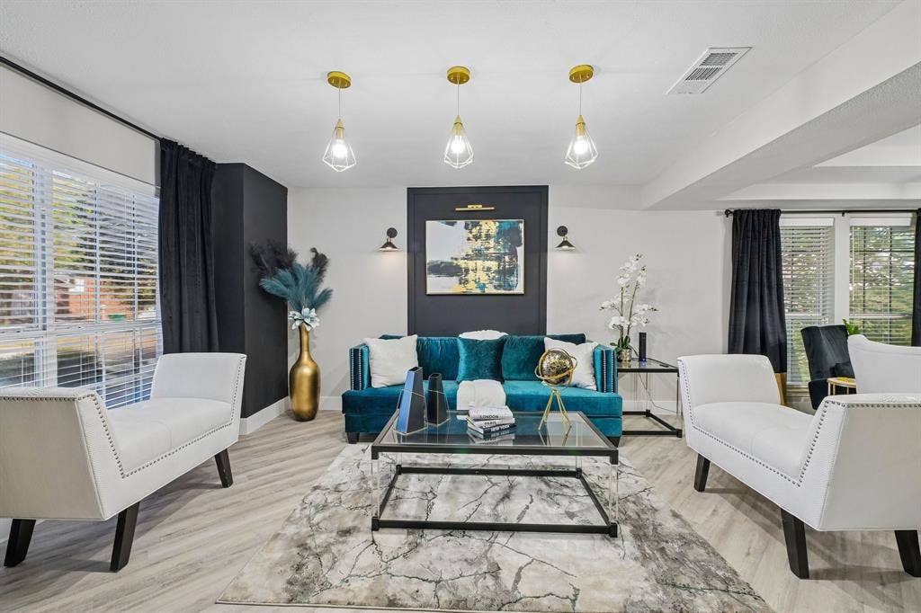 Recessed ceiling with three pendant light fixtures, light wood-finish flooring, and window blinds for natural light control