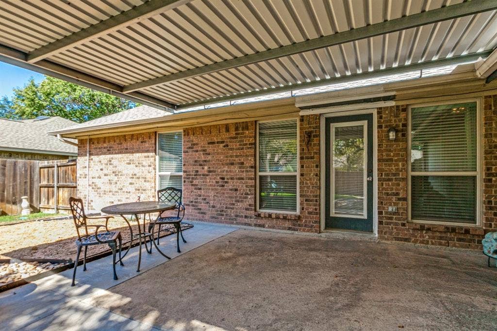 Covered concrete patio with a brick exterior, privacy fencing, and exterior windows