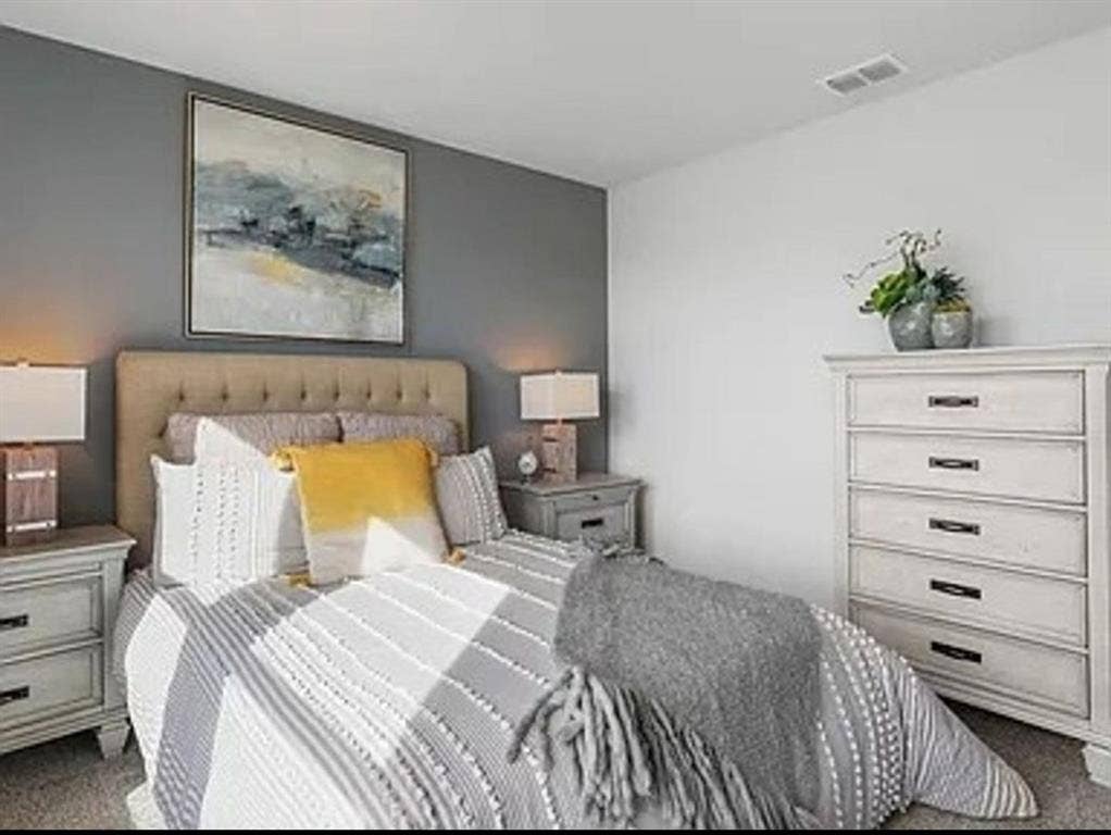 Staged Bedroom with dark colored carpet.  Home is currently vacant and does not have an accent wall color.