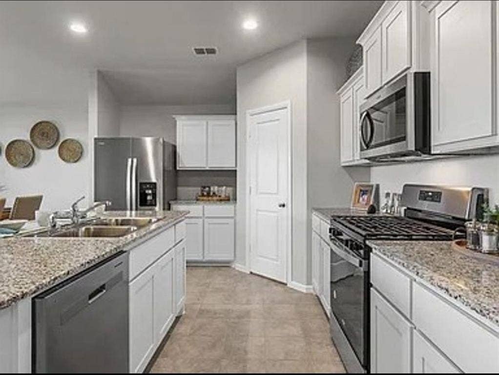 Kitchen with stainless steel appliances, recessed lighting, light stone countertops, and white cabinetry