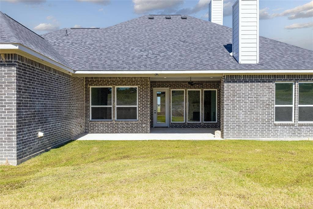 104 Oak Meadow Lane, Weatherford, TX 76085 Brick exterior with a covered patio, multiple windows, and a glass-paneled door