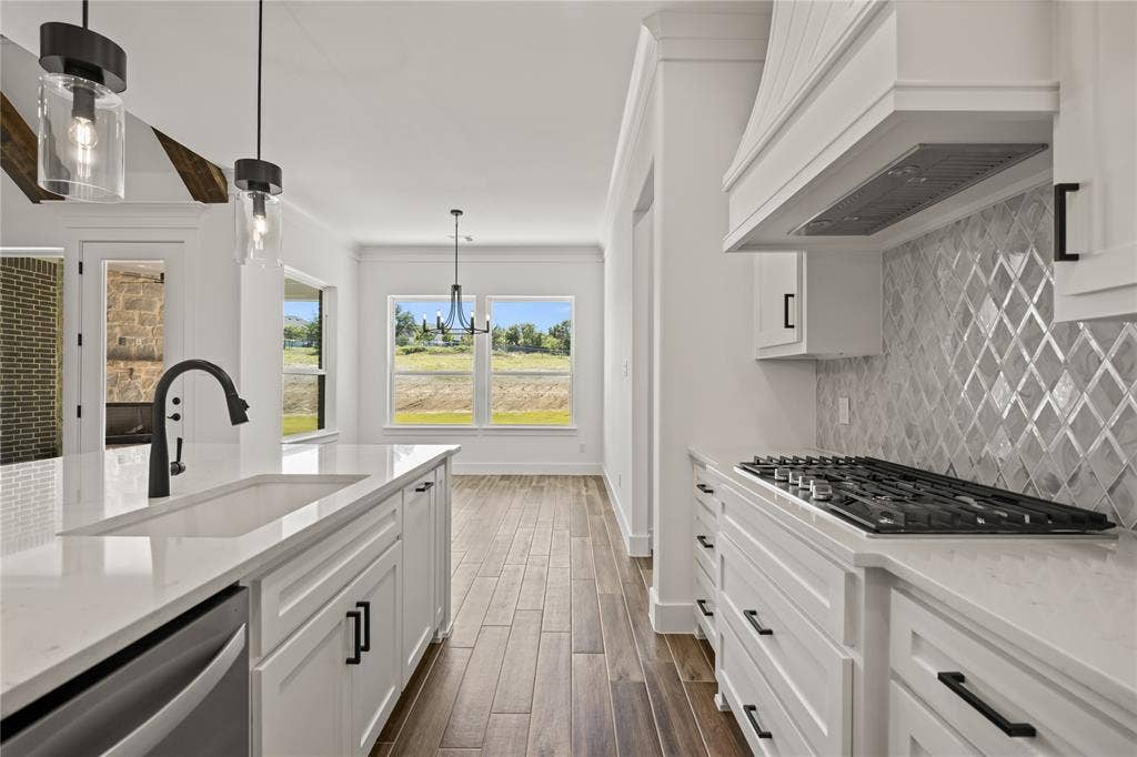 104 Oak Meadow Lane, Weatherford, TX 76085 White cabinetry with black hardware, wood-finish flooring, white countertops, glass subway tile backsplash, and a built-in gas range