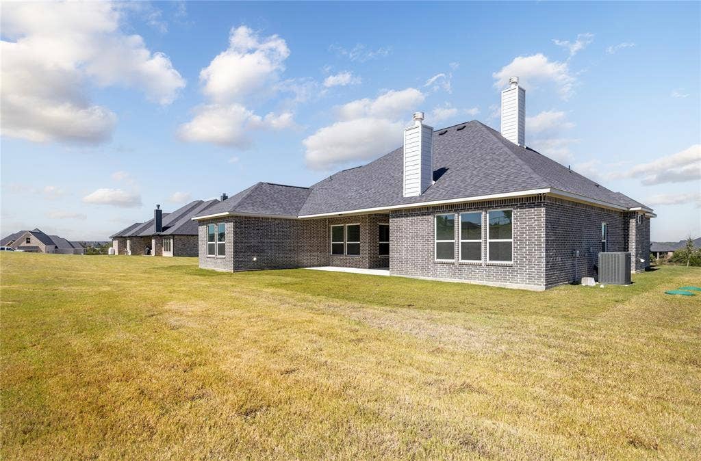 104 Oak Meadow Lane, Weatherford, TX 76085 Exterior featuring brick siding, a dark shingle roof, multiple windows, and two chimney stacks