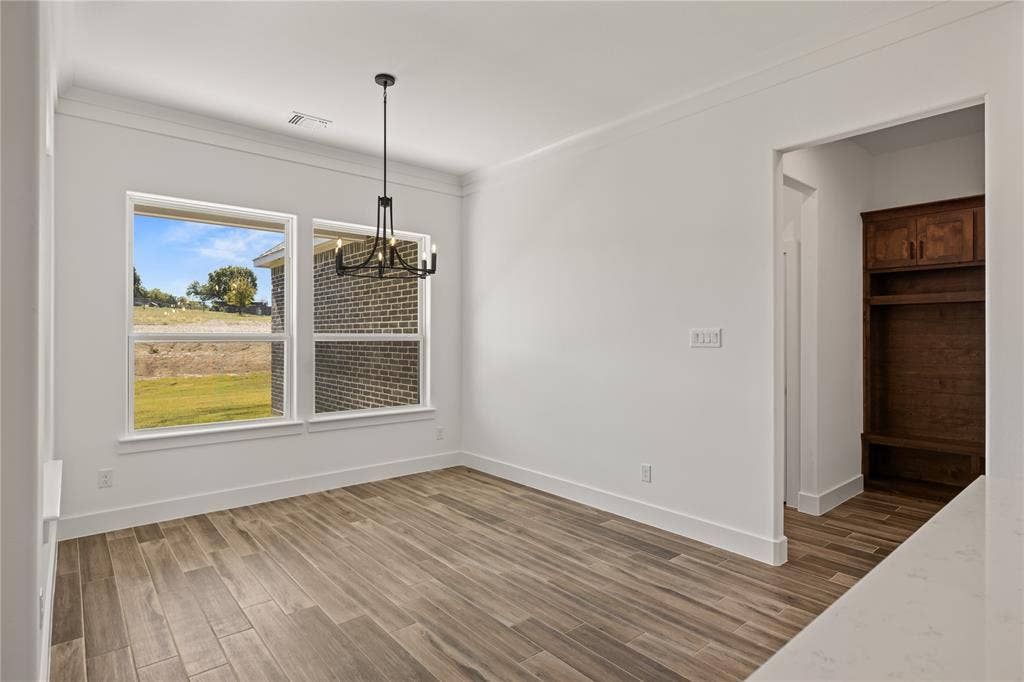 104 Oak Meadow Lane, Weatherford, TX 76085 Spacious room featuring wood-finish flooring, large windows, a modern chandelier, and crown molding