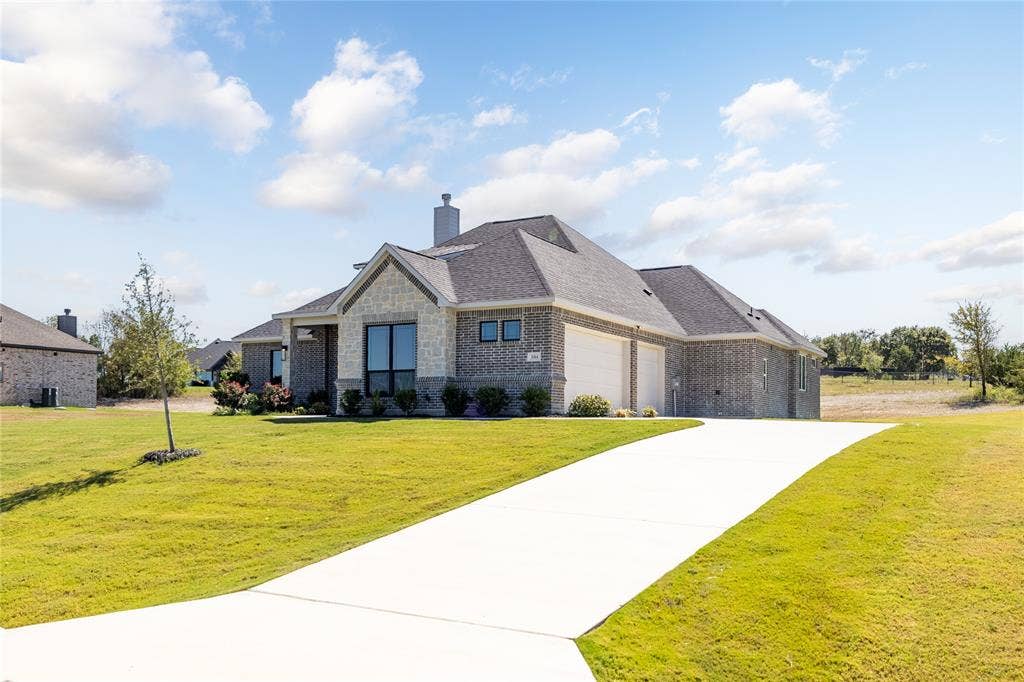 104 Oak Meadow Lane, Weatherford, TX 76085 Contemporary single-story residence with a stone and brick facade, a two-car garage, and a concrete driveway