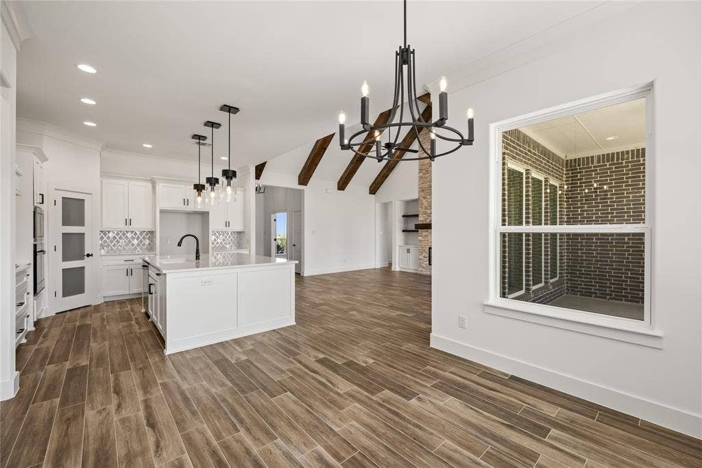 104 Oak Meadow Lane, Weatherford, TX 76085 Open-concept living space with wood-finish flooring, white cabinetry, a kitchen island, and a decorative chandelier
