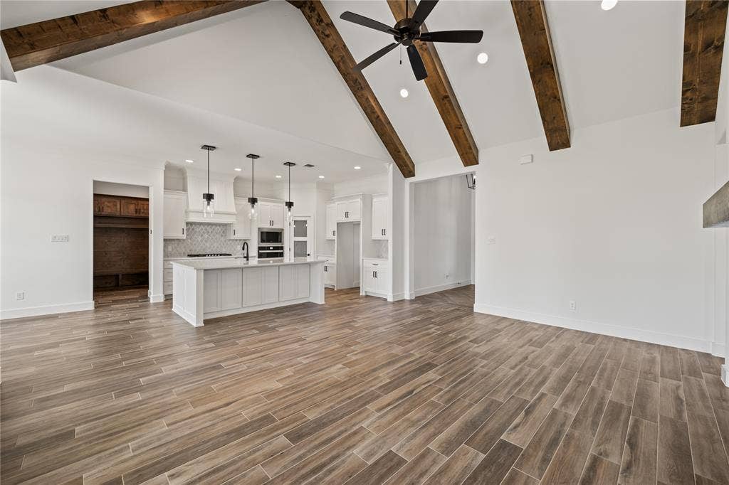 104 Oak Meadow Lane, Weatherford, TX 76085 Vaulted ceilings with exposed beams, wood-finish flooring, recessed lighting, kitchen island with built-in sink, and pendant lighting