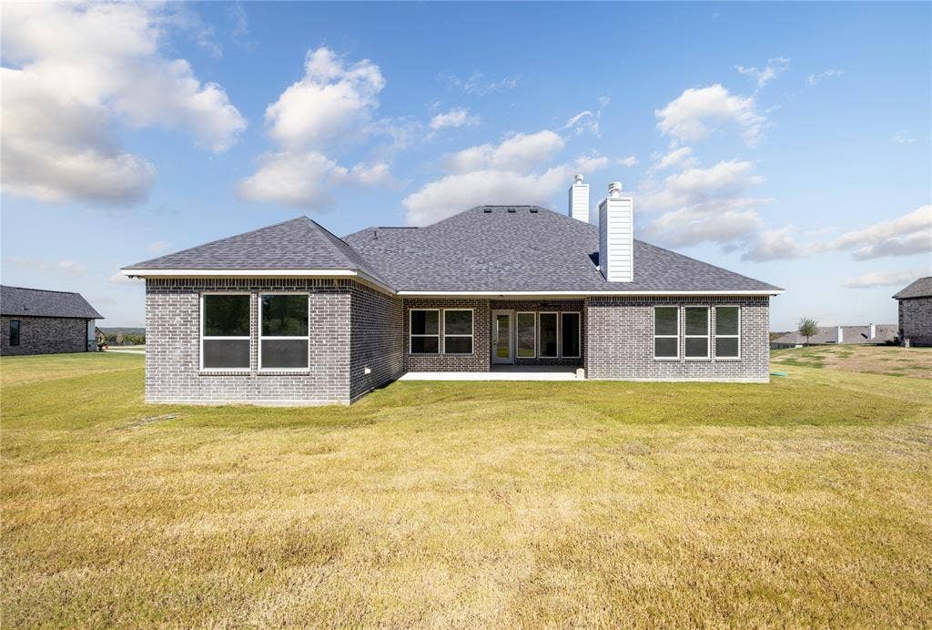 104 Oak Meadow Lane, Weatherford, TX 76085 Brick exterior featuring multiple windows, a covered patio, and a shingle roof