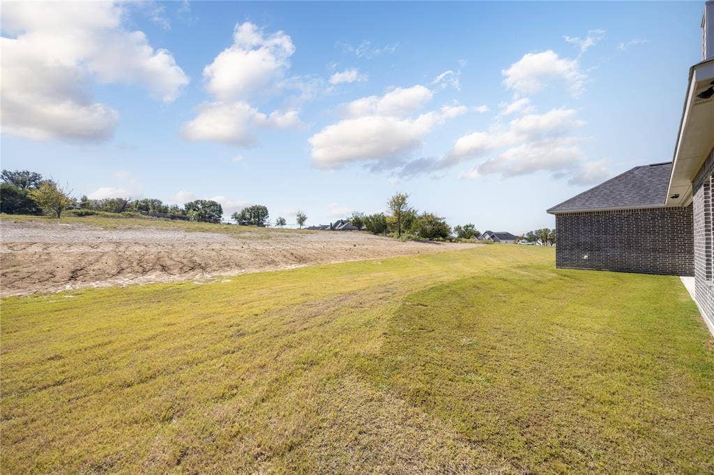 104 Oak Meadow Lane, Weatherford, TX 76085 Expansive grassy area with a partial brick exterior