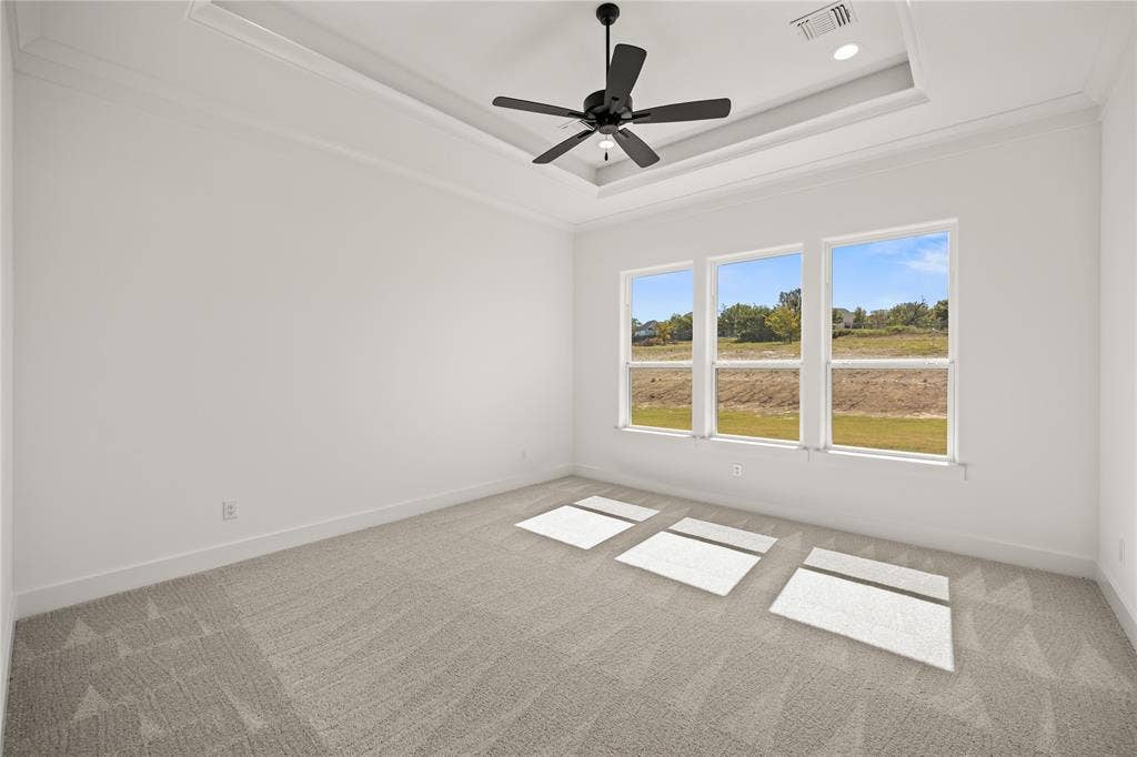 104 Oak Meadow Lane, Weatherford, TX 76085 Recessed ceiling with crown molding, three large windows, ceiling fan, and light-toned carpet flooring
