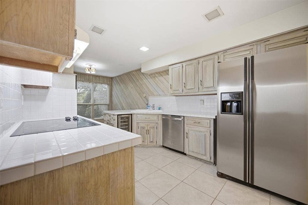 Kitchen featuring tile countertops, stainless steel refrigerator, stainless steel dishwasher, and built-in electric cooktop