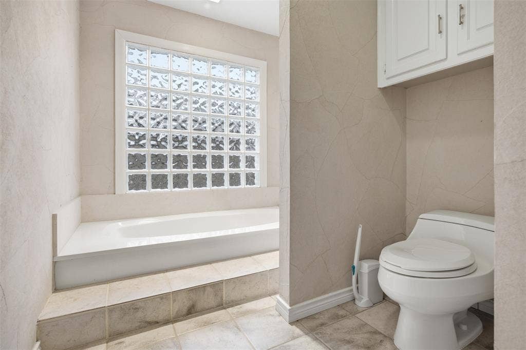 Built-in bathtub with a tile surround and glass block window