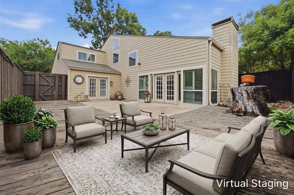 Expansive outdoor decking, double-door entries, an exterior chimney structure, and light-toned siding