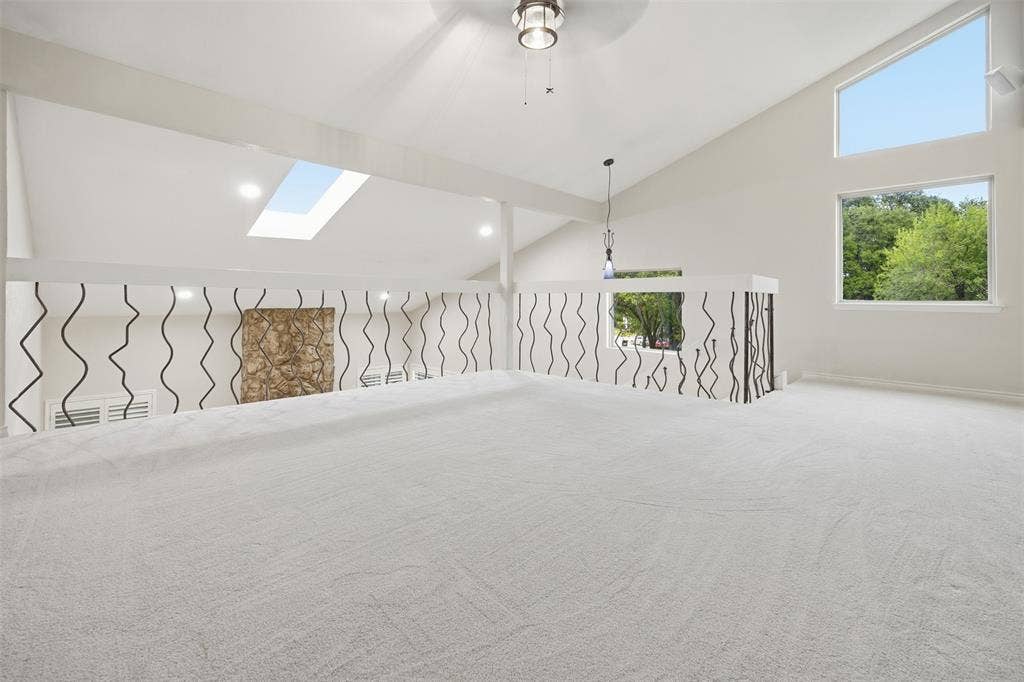 Vaulted ceilings with a skylight, recessed lighting, and a decorative railing