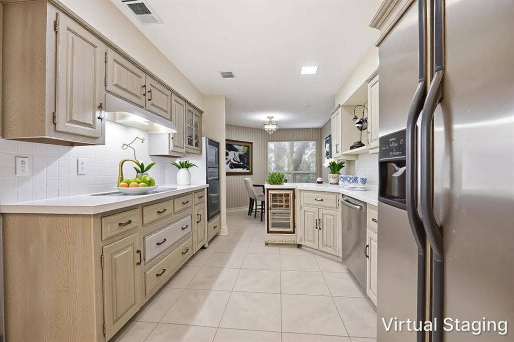 Kitchen featuring extensive light-toned cabinetry, stainless steel appliances, a built-in wine refrigerator, white countertops, and a tile backsplash