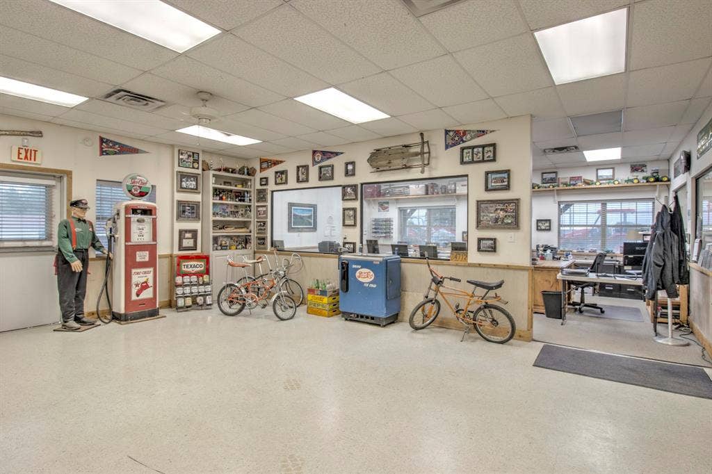 Open-concept space featuring a dropped tile ceiling, recessed panel lighting, polished concrete flooring, built-in shelving, and multiple windows providing natural illumination