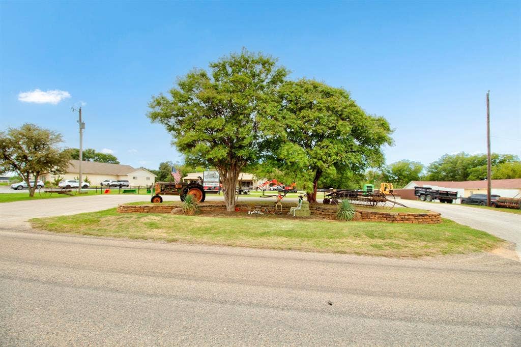 Expansive grounds featuring a raised stone retaining wall, mature trees, and paved access roads