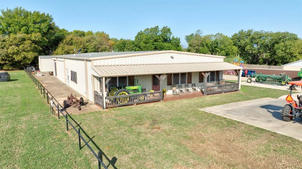 Metal exterior structure with a covered front porch, concrete patio space, and perimeter metal fencing