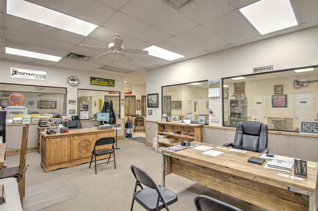 Interior office space featuring dropped ceilings with inset lighting, wall-to-wall carpeting, multiple glass partition walls, and built-in wood-finish cabinetry