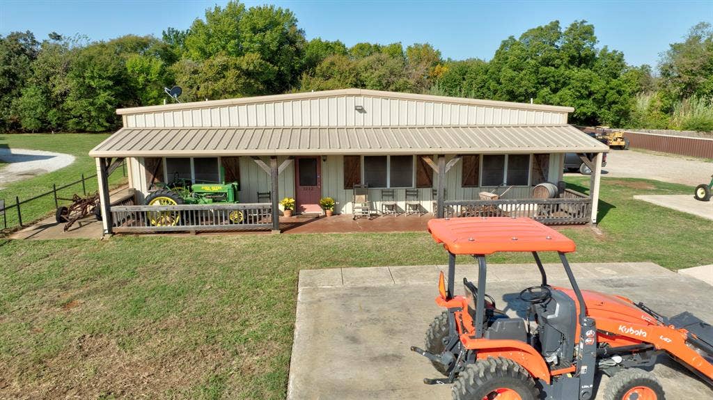 Metal-siding exterior featuring a covered front porch, concrete patio space, and timber-post supports