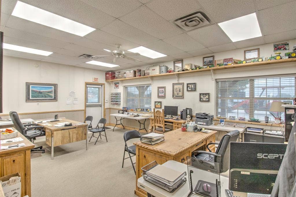 Interior space featuring high-output recessed lighting, wall-mounted display shelving, large multi-pane windows, and neutral carpeting