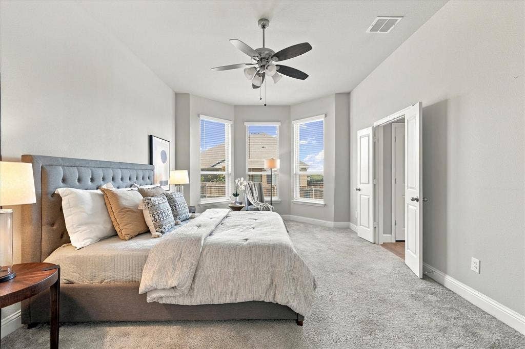 High ceilings with a ceiling fan, bay windows with blinds, light-colored walls, carpeted flooring, and double doors