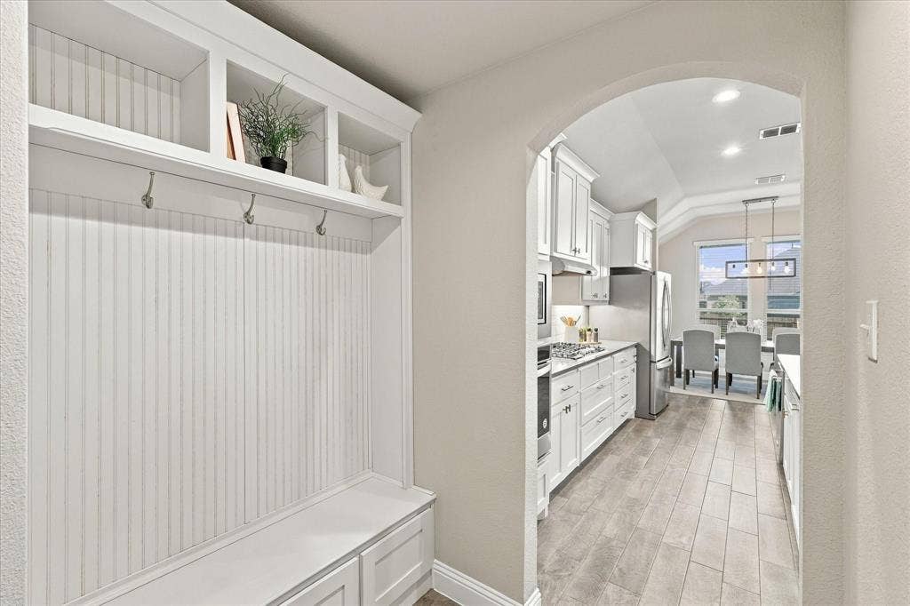 Built-in white mudroom bench with storage, overhead shelving, and coat hooks