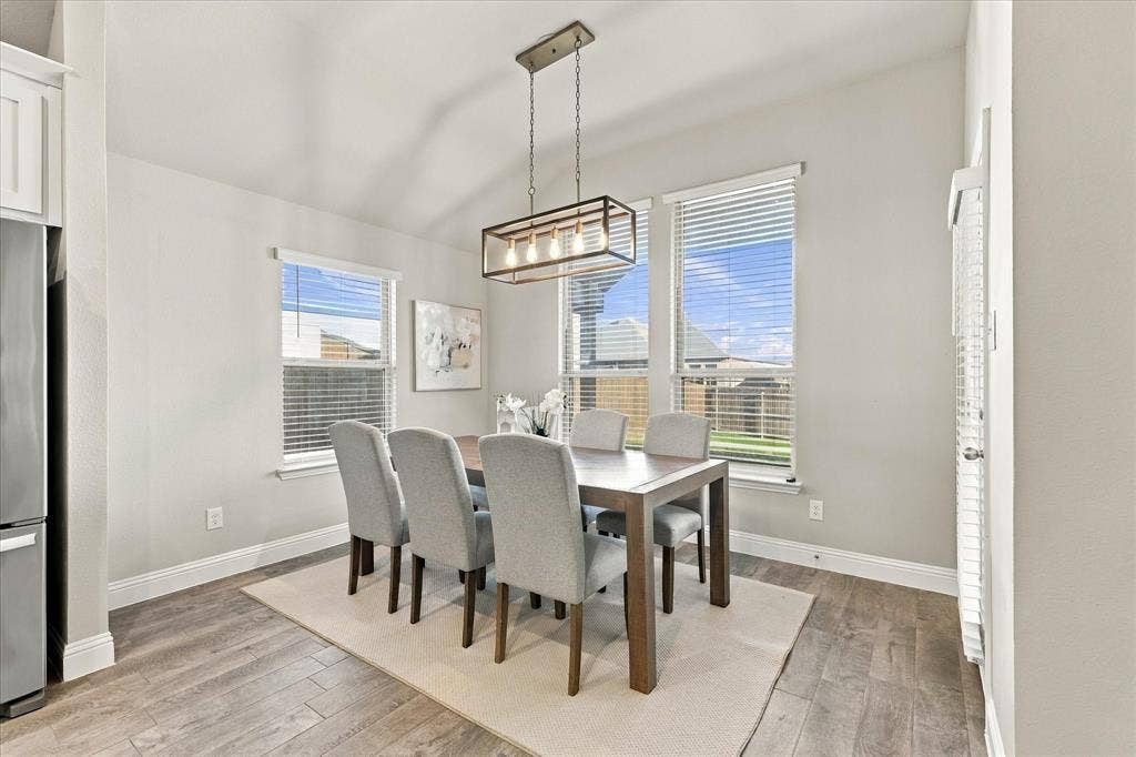 Wood-finish flooring, multiple windows with blinds, recessed ceiling, and a modern rectangular chandelier