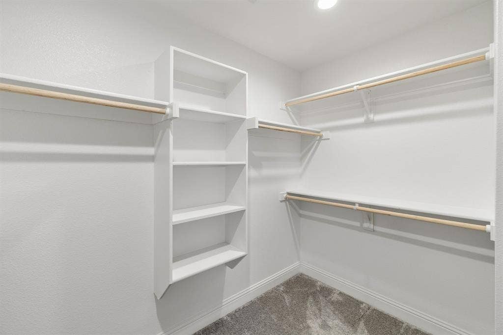 Built-in shelving unit, multiple clothing rods, recessed lighting, and carpet flooring