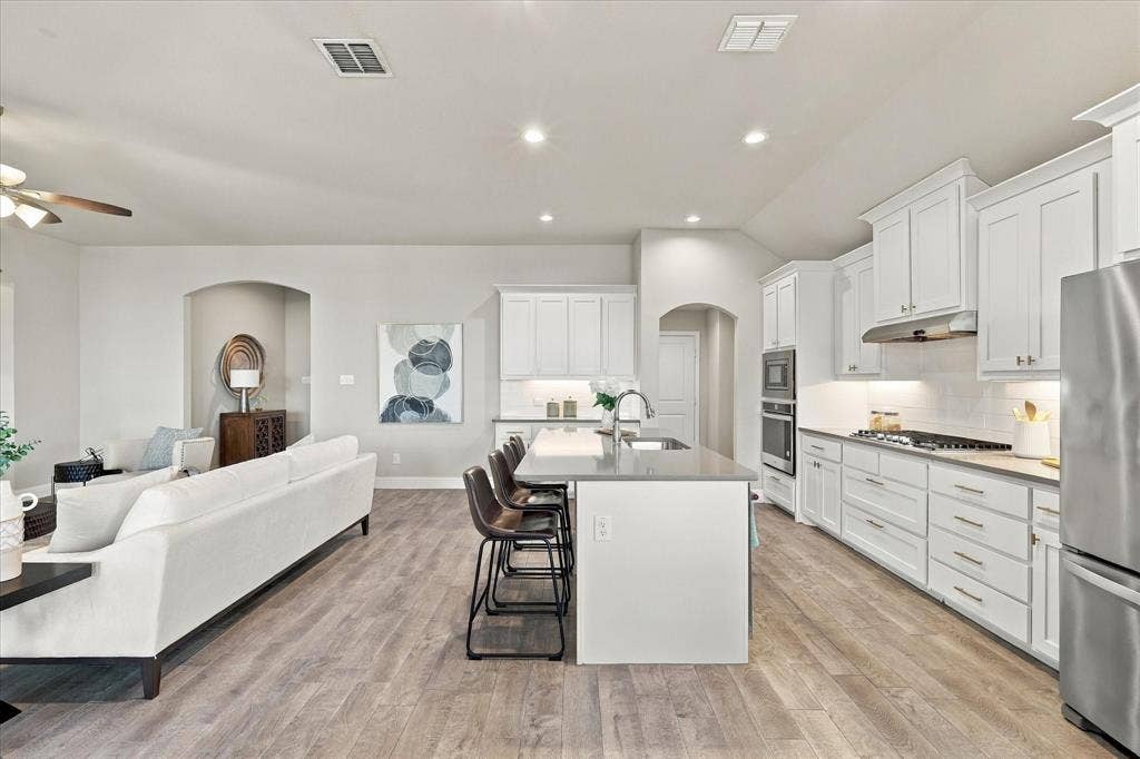Open-concept layout featuring wood-finish flooring, recessed lighting, and an arched doorway