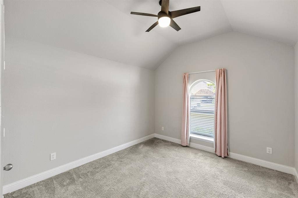 Vaulted ceiling with an attached ceiling fan, arched window with horizontal blinds, and gray carpeting