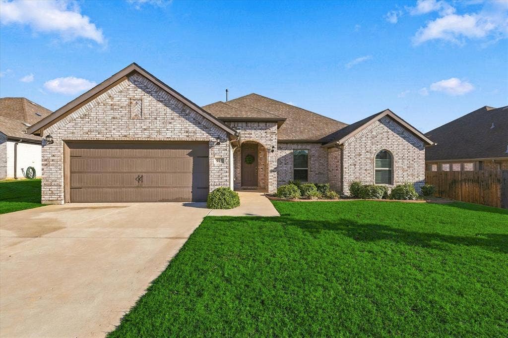 Brick exterior with light-colored masonry, attached two-car garage, arched entry, and arched window accents