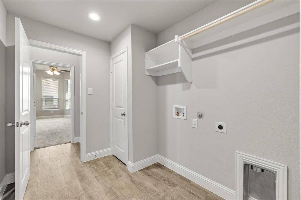 Utility area featuring wood-finish flooring, white trim, recessed lighting, and built-in shelving with a clothes rod