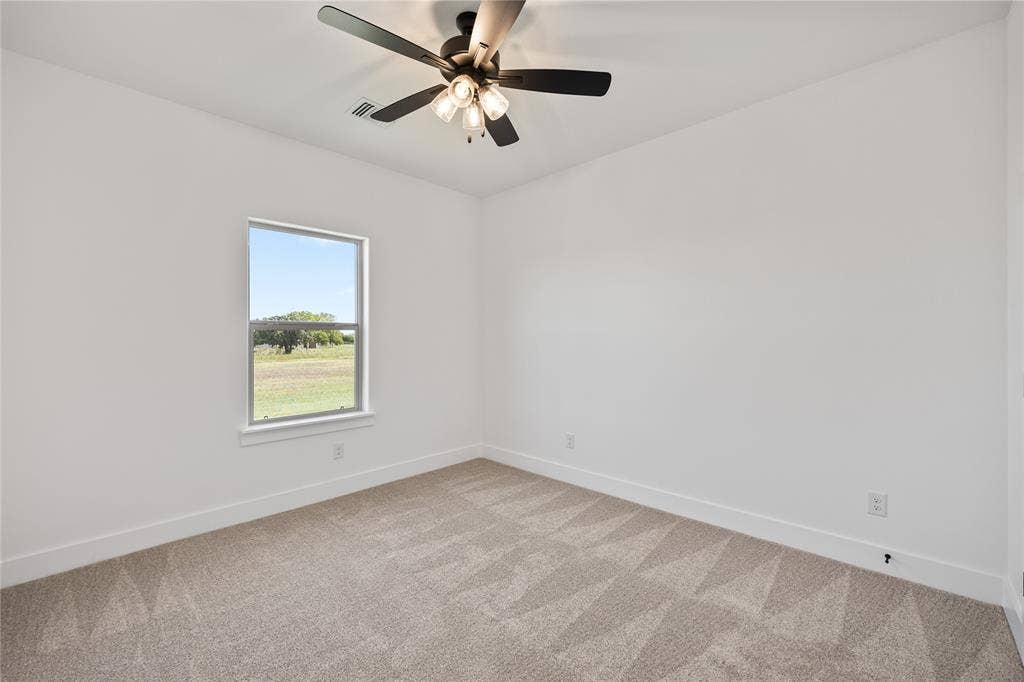 Neutral carpet flooring with a geometric pattern, single window, and a ceiling fan with integrated lighting