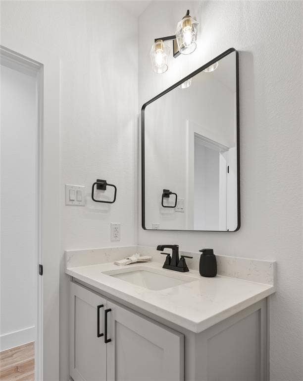 Vanity with light-toned countertop, undermount sink, matte black faucet, and light gray cabinetry