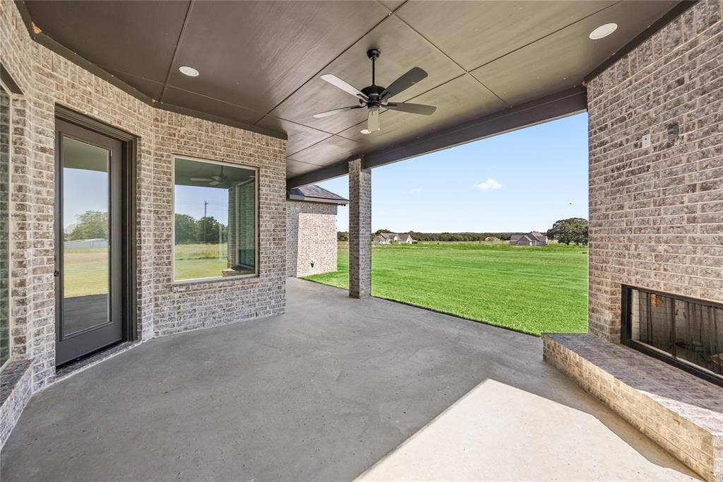 Expansive covered patio featuring a ceiling fan, recessed lighting, and a built-in outdoor fireplace