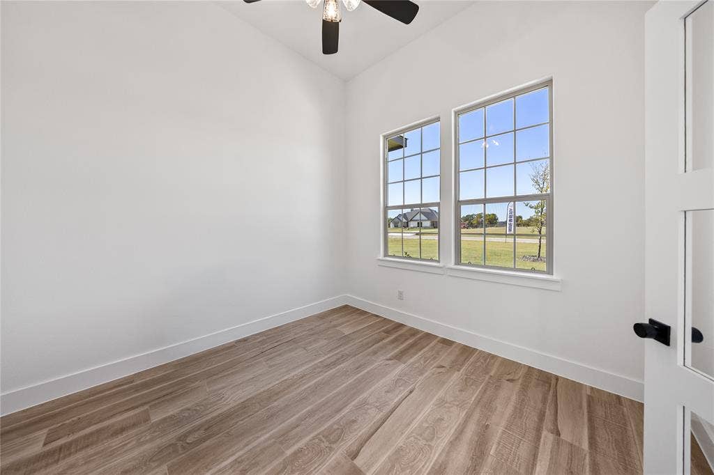 Vaulted ceiling, two paneled windows, wood-finish flooring, and a white interior door with matte black hardware