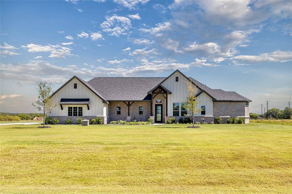 Modern farmhouse exterior with board and batten siding, brick accents, dark-framed windows, a covered front entry, and a dark shingle roof