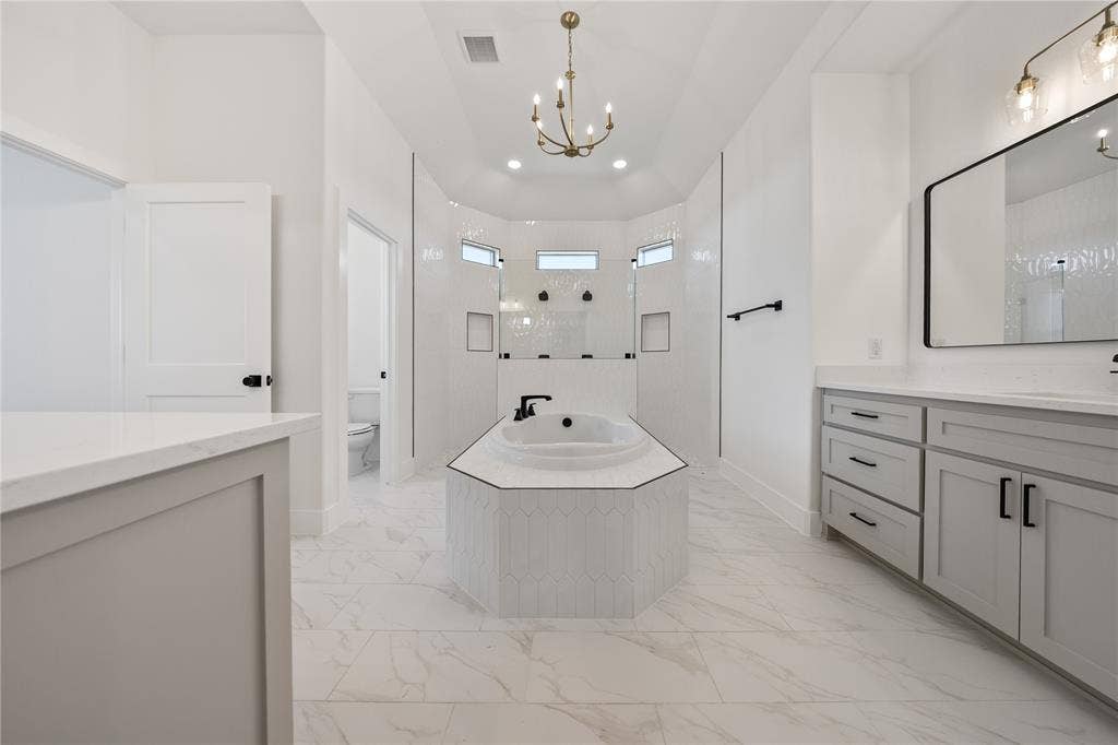 Spacious bath featuring a built-in soaking tub, dual vanity with undermount sinks, and a walk-in shower with tile surround
