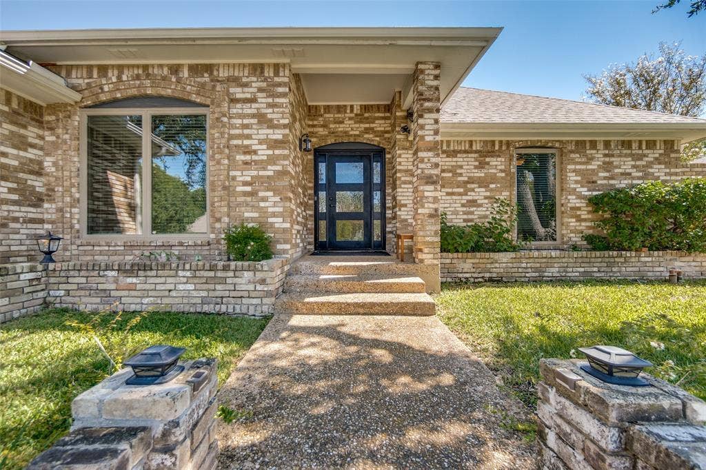 7414 Windmill Lane, Garland, TX 75044 Brick exterior with a covered entry, arched window, and a modern glass-paneled door