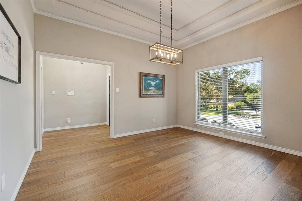 7414 Windmill Lane, Garland, TX 75044 Tray ceiling with crown molding, wood-finish flooring, rectangular window, and a linear chandelier
