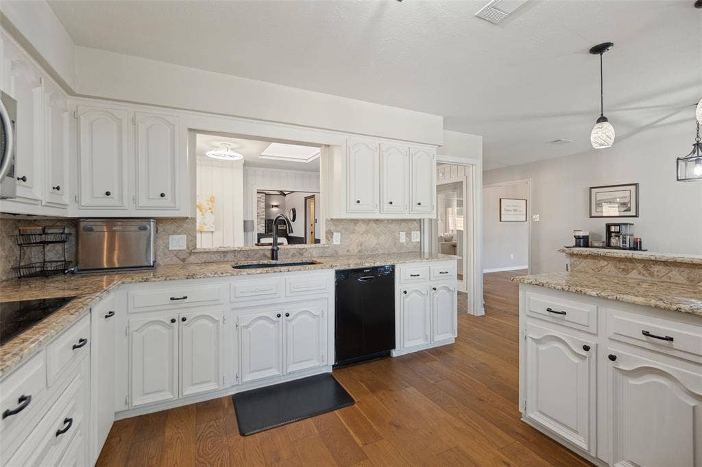 7414 Windmill Lane, Garland, TX 75044 Kitchen featuring white cabinetry, granite countertops, tile backsplash, wood-finish flooring, and a pass-through window
