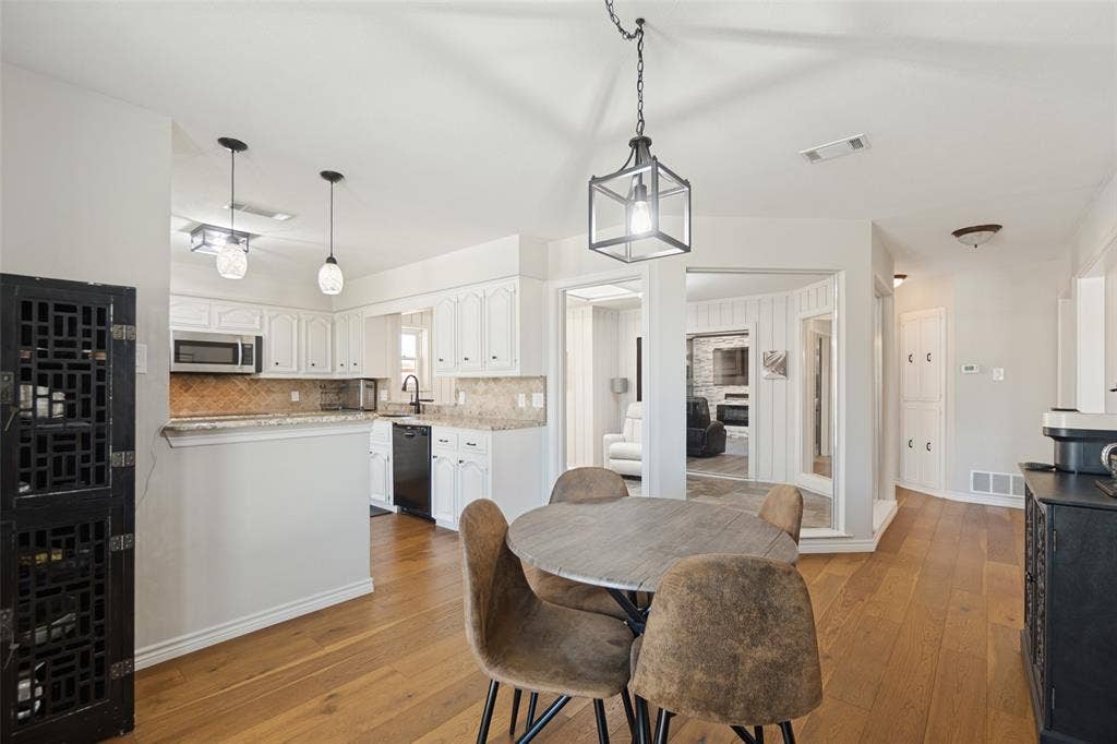 7414 Windmill Lane, Garland, TX 75044 Kitchen featuring white cabinetry, stainless steel microwave, black dishwasher, and a stone-look backsplash