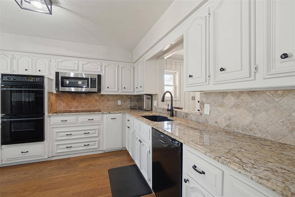 7414 Windmill Lane, Garland, TX 75044 Kitchen featuring white cabinetry, granite countertops, double wall ovens, a built-in microwave, and wood-finish flooring