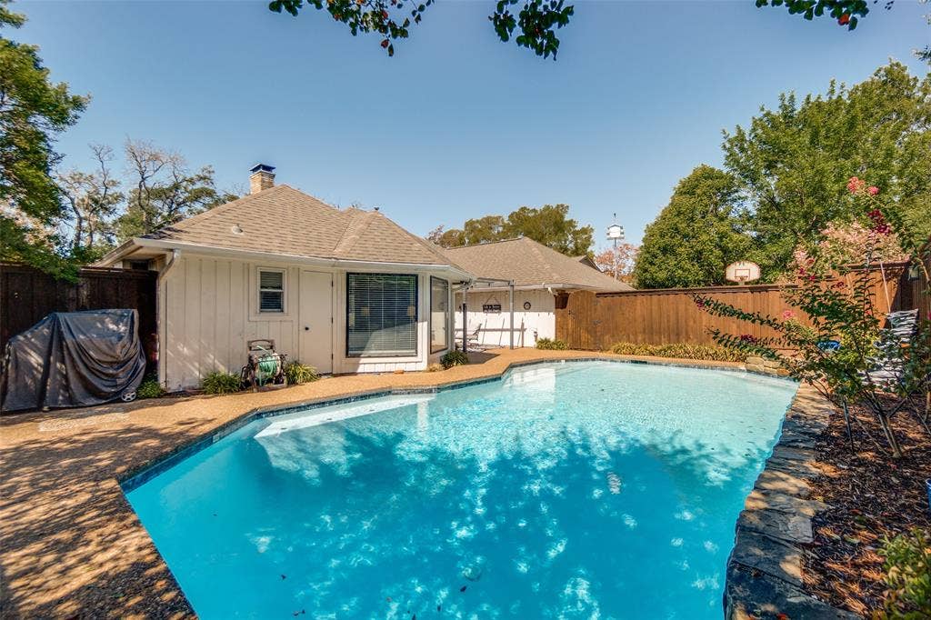 7414 Windmill Lane, Garland, TX 75044 Outdoor swimming pool with concrete decking, wood privacy fence, and mature trees