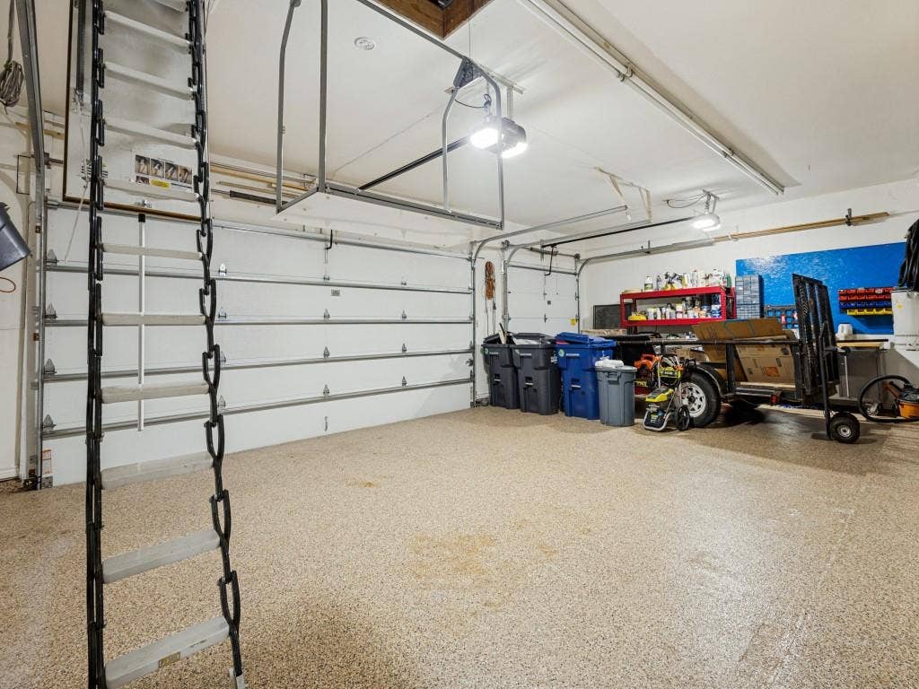 Garage featuring two overhead doors, a finished floor, overhead lighting, and built-in shelving