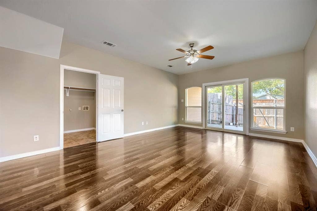 Wood-finish flooring, vaulted ceiling, ceiling fan, sliding glass door, and arched windows