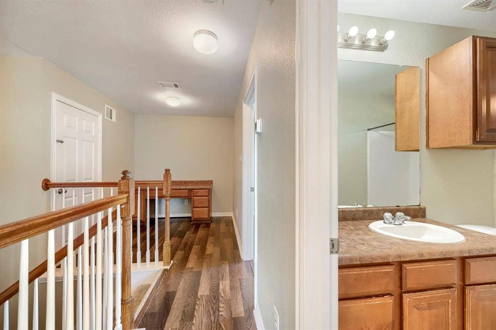 Wood-finish flooring throughout, white baluster staircase with wood handrail, and built-in desk
