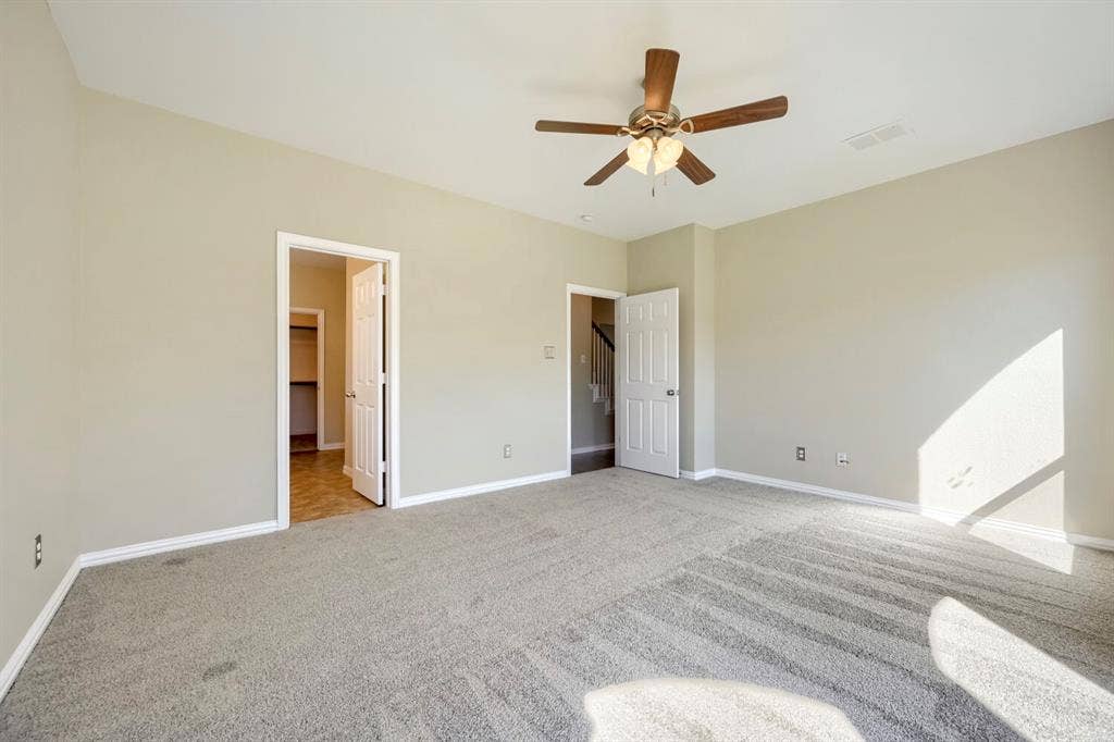 Carpeted flooring, neutral wall tones, ceiling fan with integrated lighting, white trim, and white paneled doors